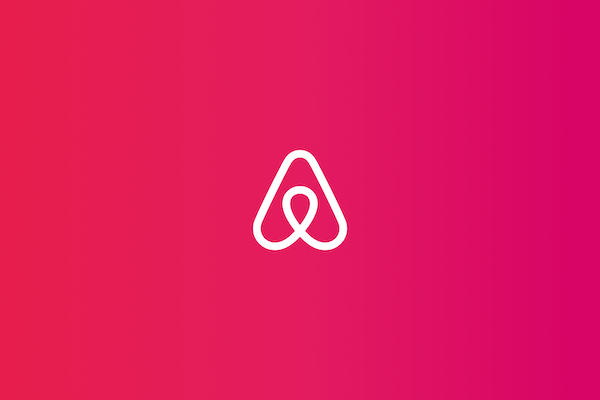 White Airbnb logo over a colorful gradient.