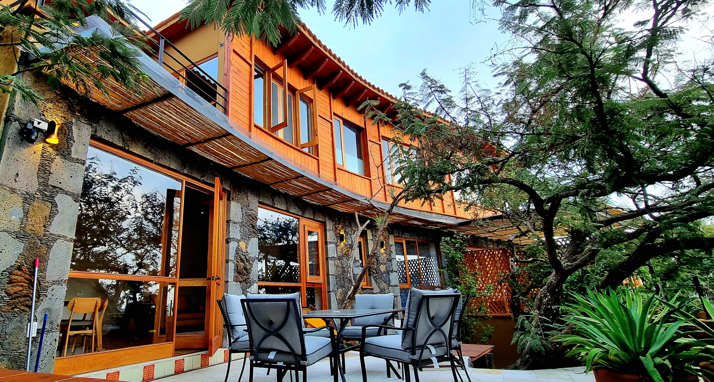 Charming stone and wood villa with a patio set surrounded by lush greenery.