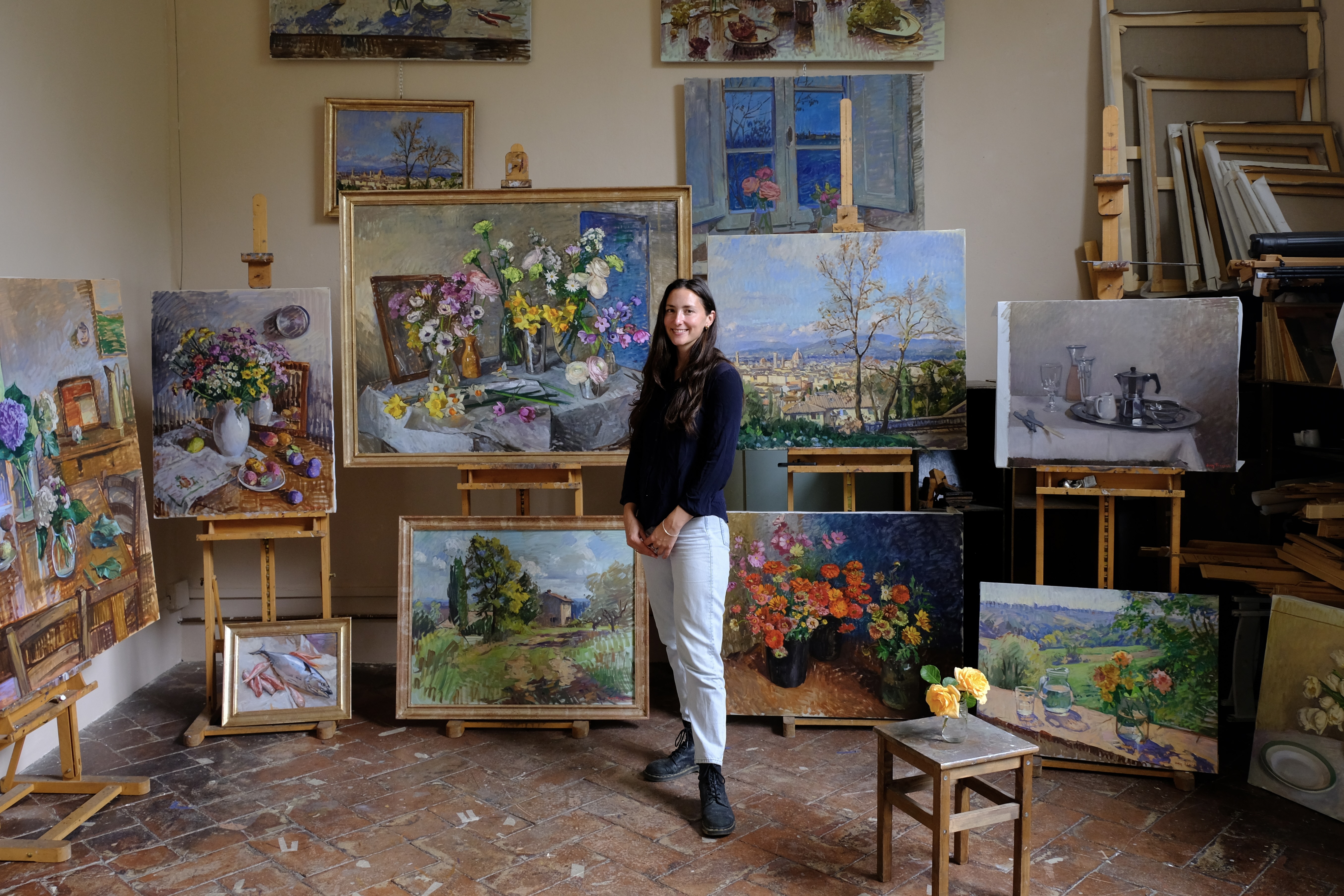 Woman artist standing in front of multiple paintings
