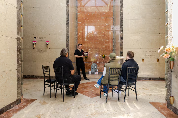 A man showing a group a photo at a cemetery during a tour