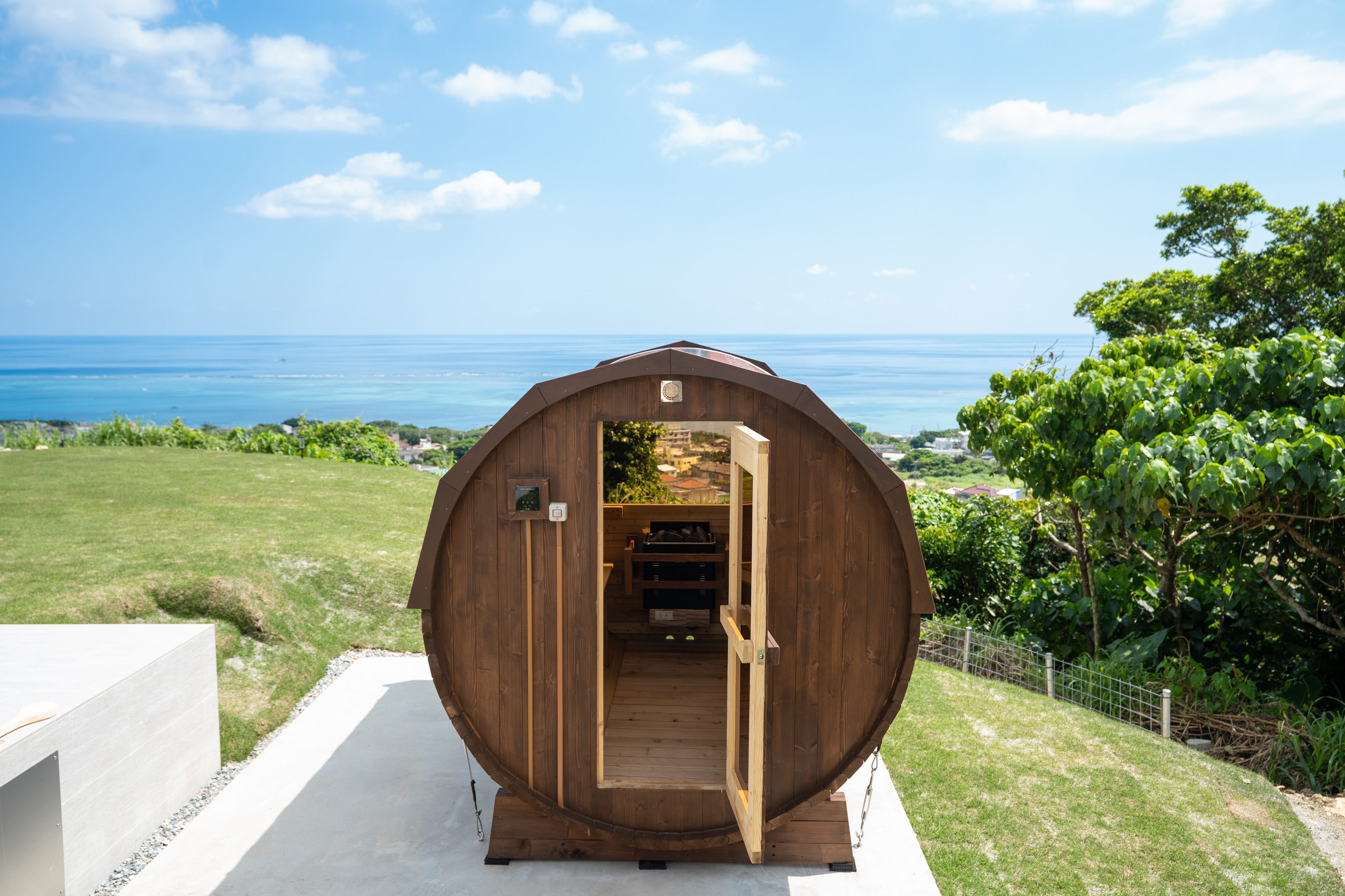 A unique barrel-shaped wooden sauna sits on a hilltop with panoramic sea views.