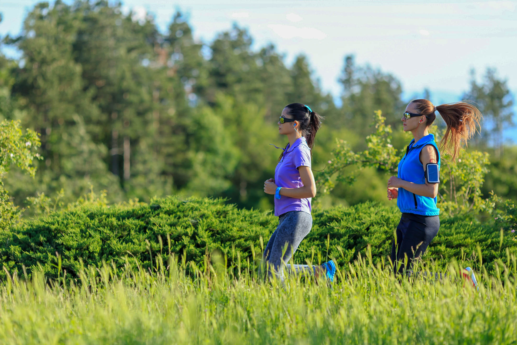 Side view of two friends running in nature Dos mujeres corriendo una detrás de otra en la naturaleza