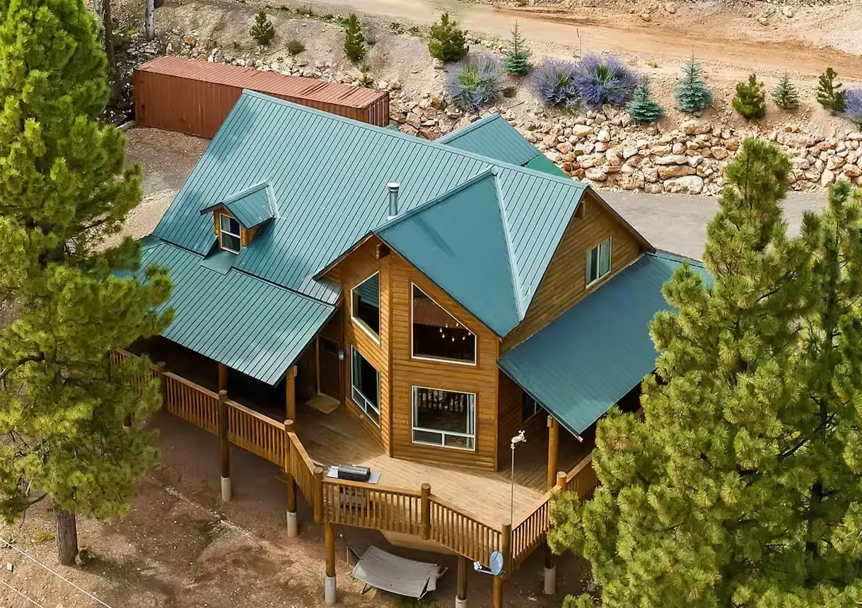 Large cabin surrounded by green trees.