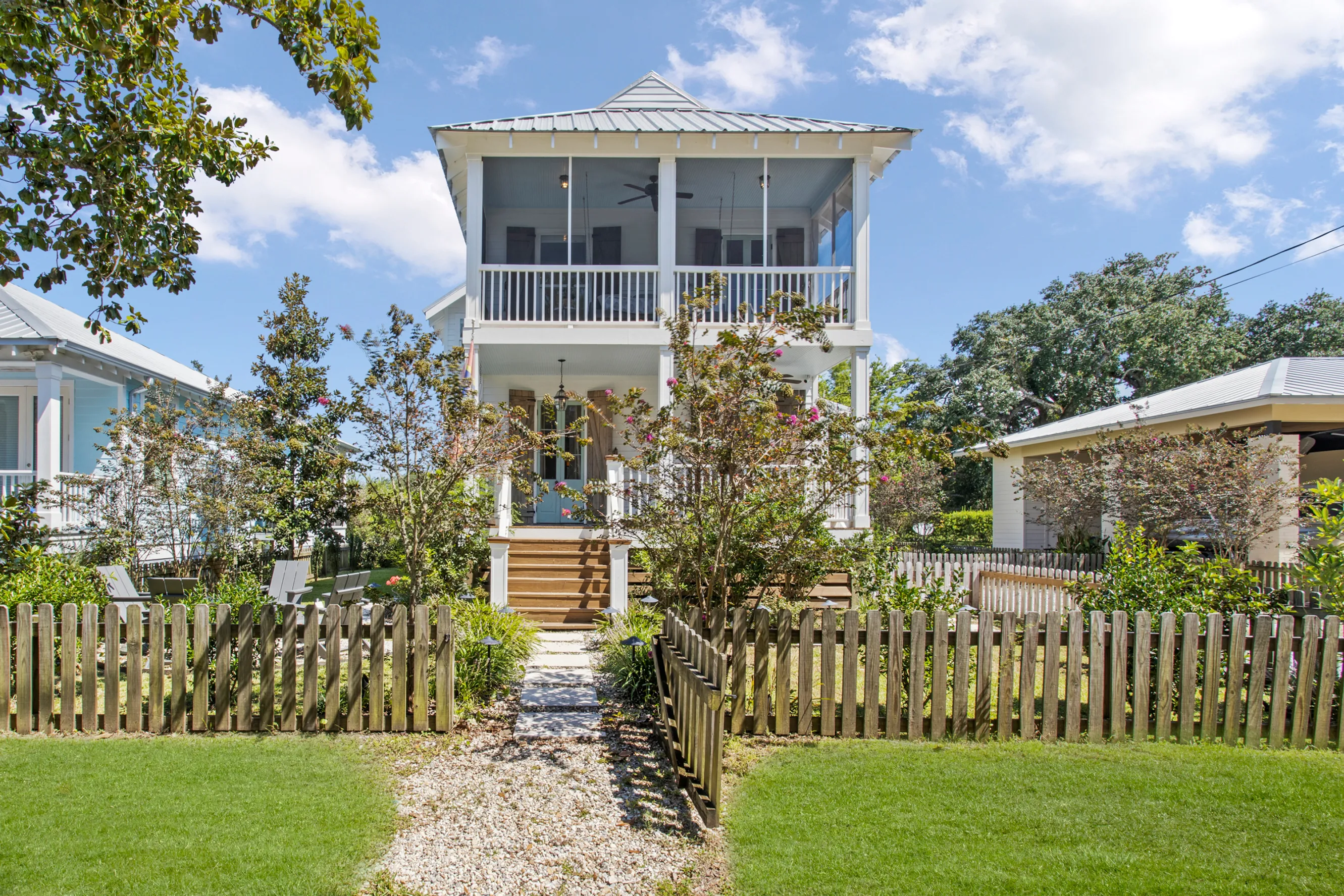 A beach bungalow with two porches surrounded by green grass.