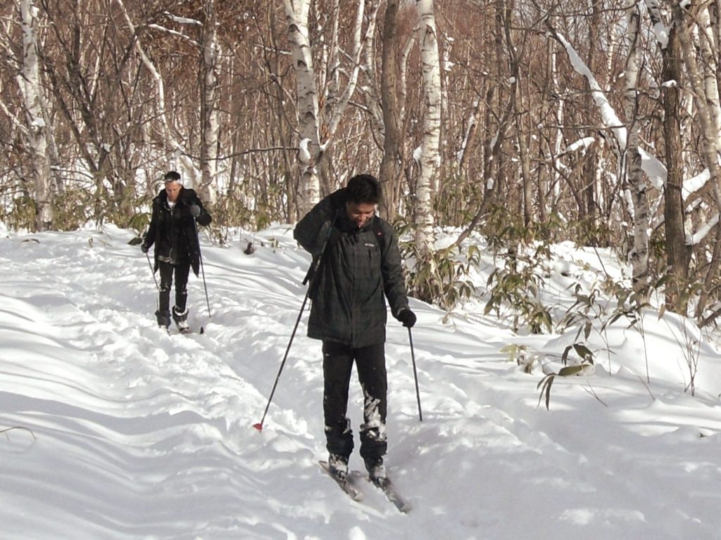Two people cross country skiing in the mountains.
