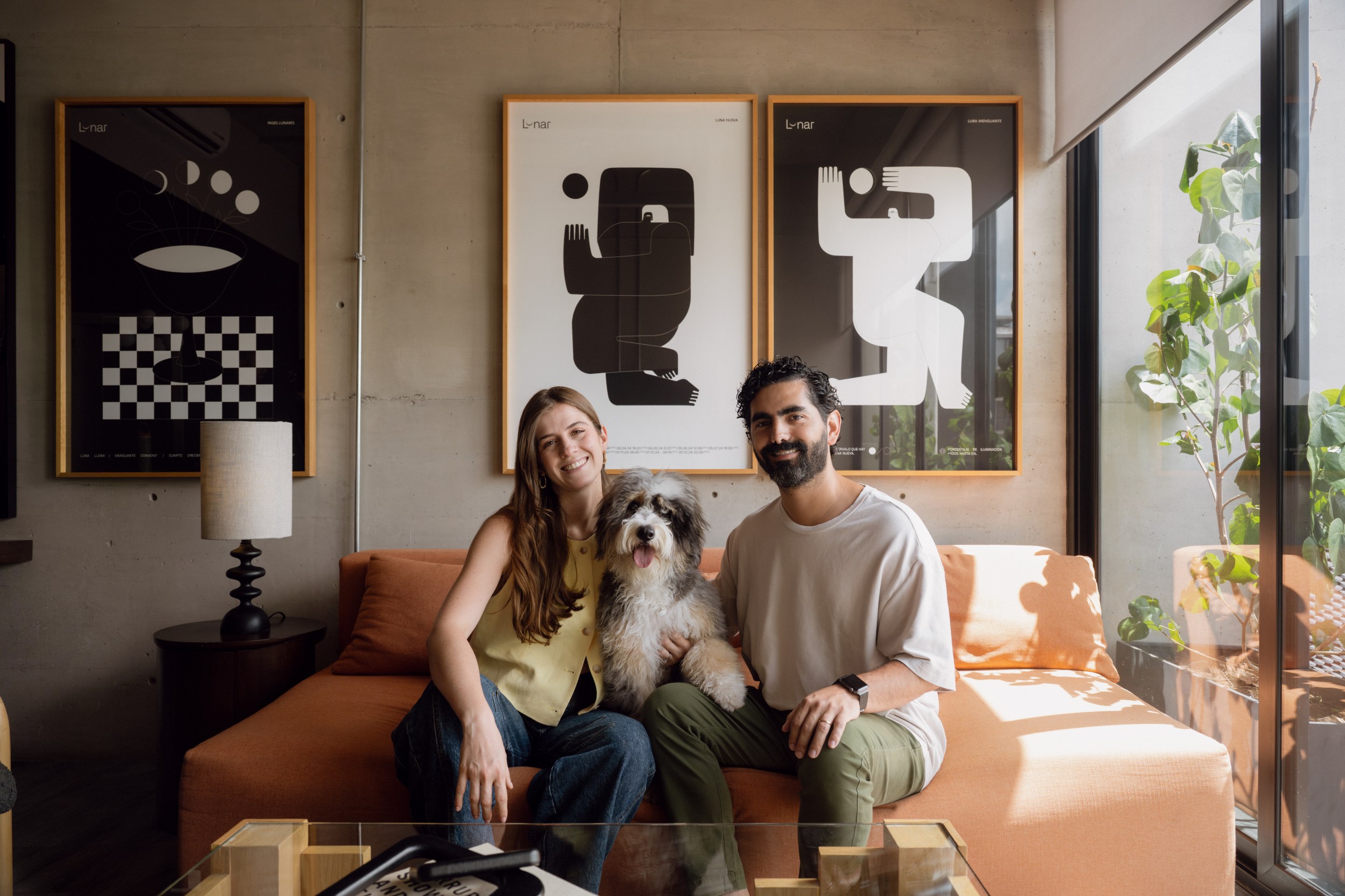Couple of man and woman sitting in a sofa with a dog in the middle