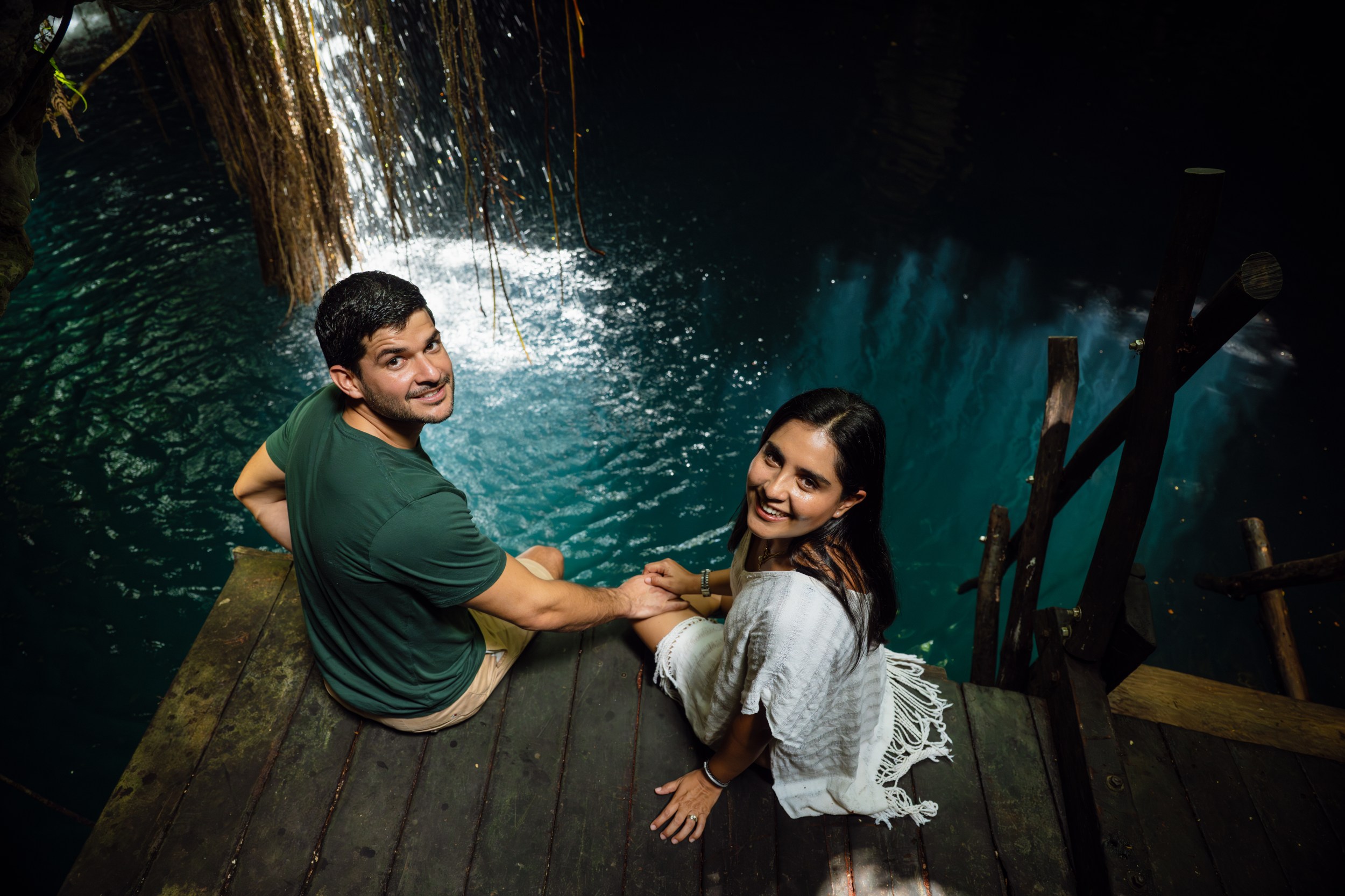 DSC_5699 Pareja de hombre y mujer sosteniendo manos sentados al borde de un cenote