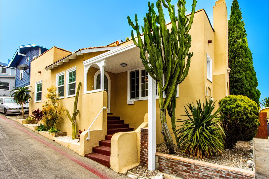 A yellow coastal home with cacti surrounding it.