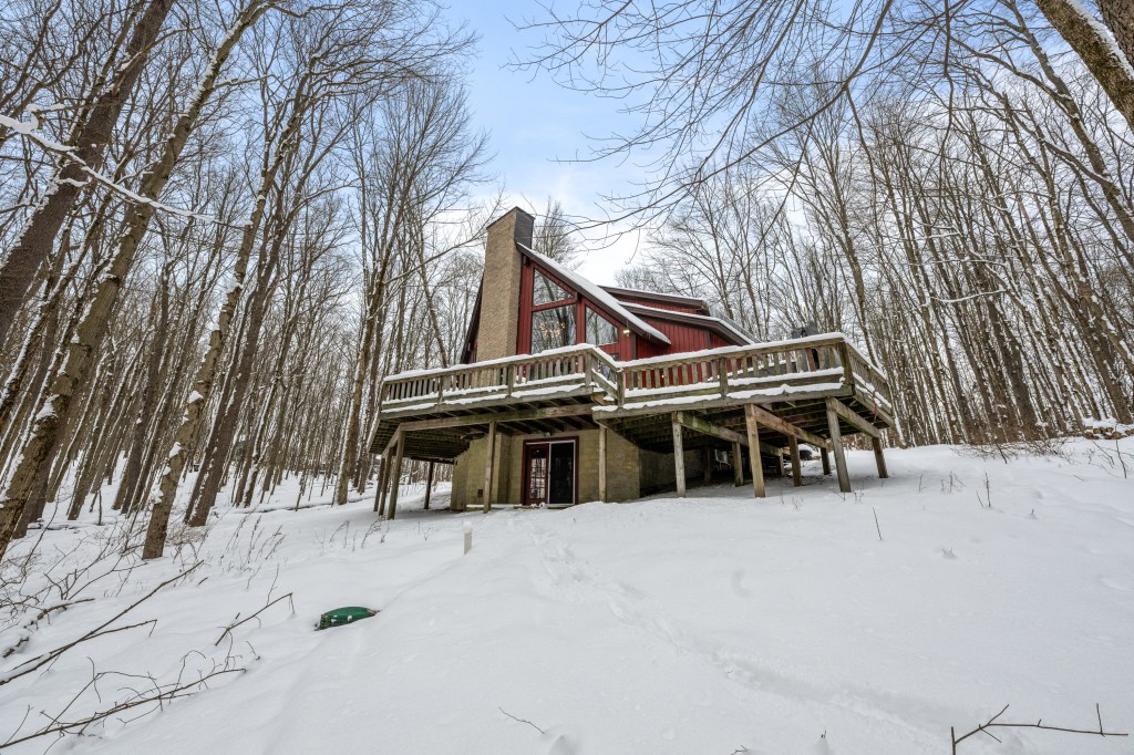 Large cabin covered in snow in the middle of the woods.