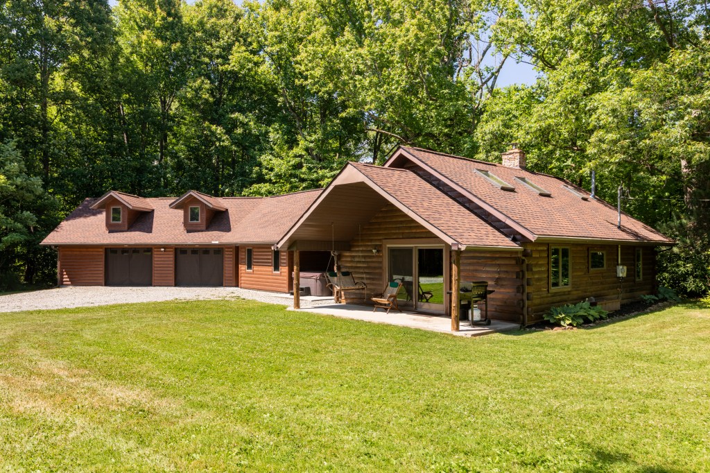 A large wooden cabin surrounded by green trees.