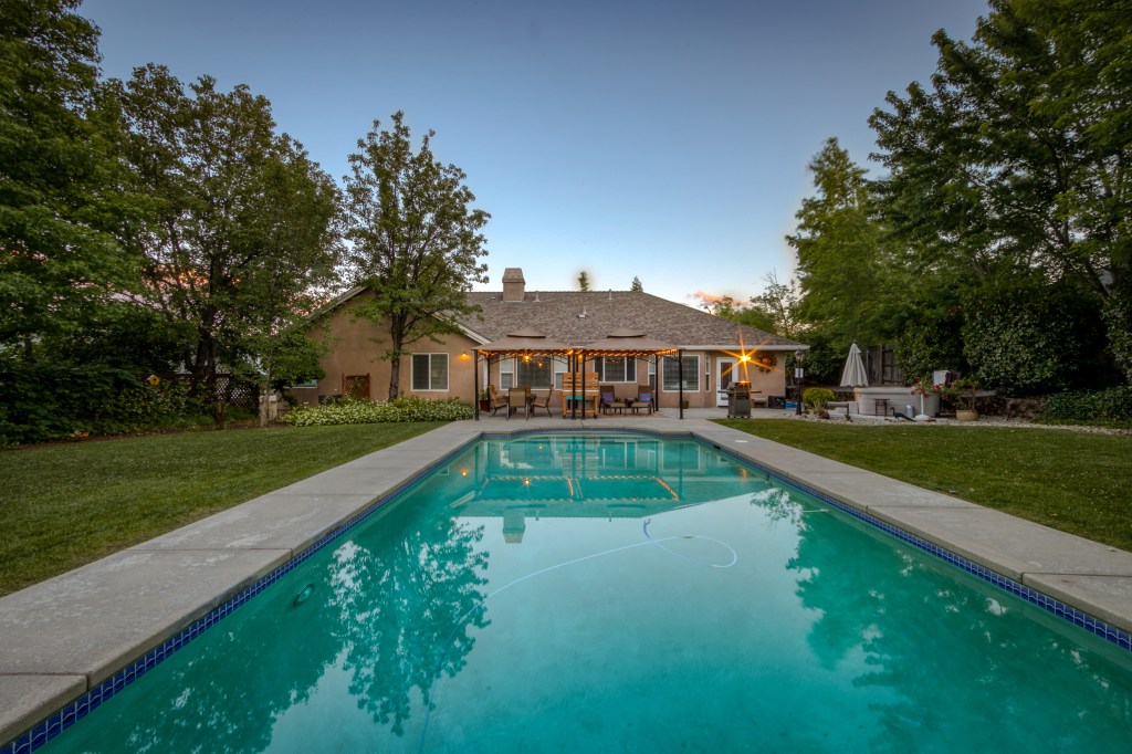 Terracotta house with a large pool in front of it.