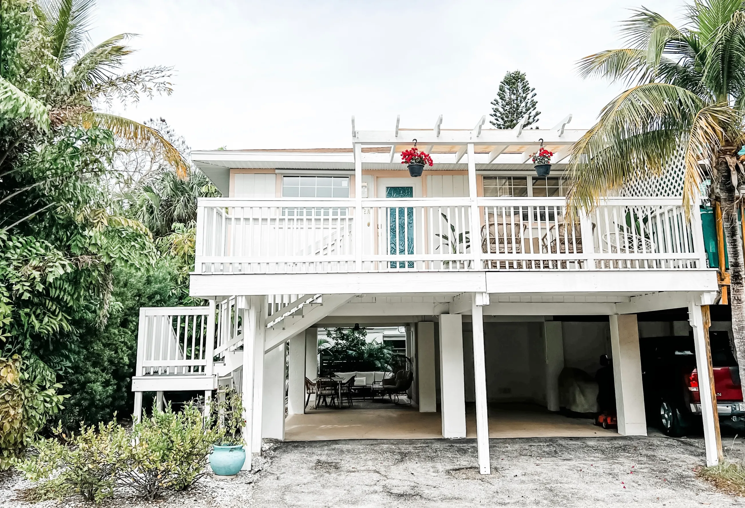 White villa with a front porch surrounded by palm trees.