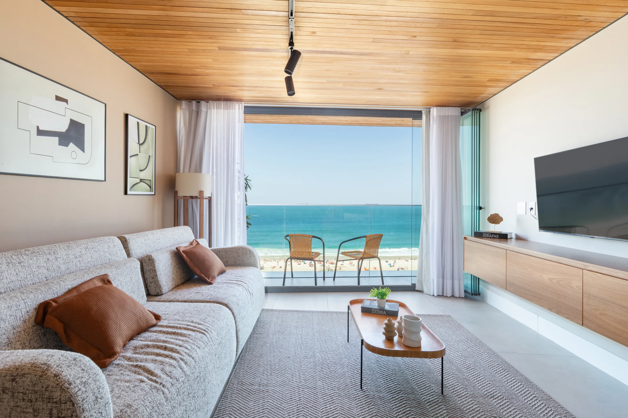 Contemporary living room with a panoramic glass wall offering stunning ocean views, minimalistic décor, and a cozy sofa.